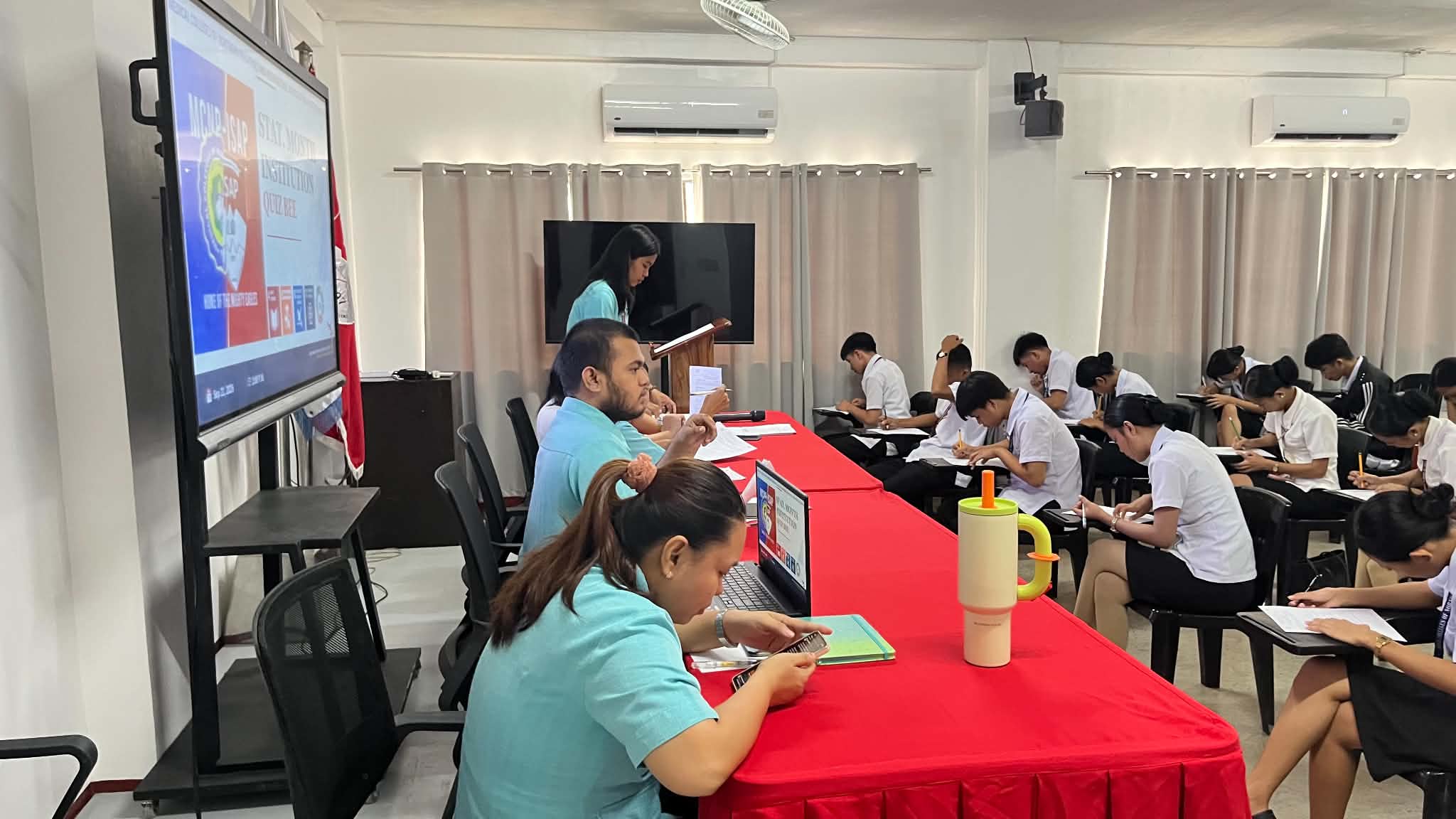 Contestants seated at competition tables working through statistics questions