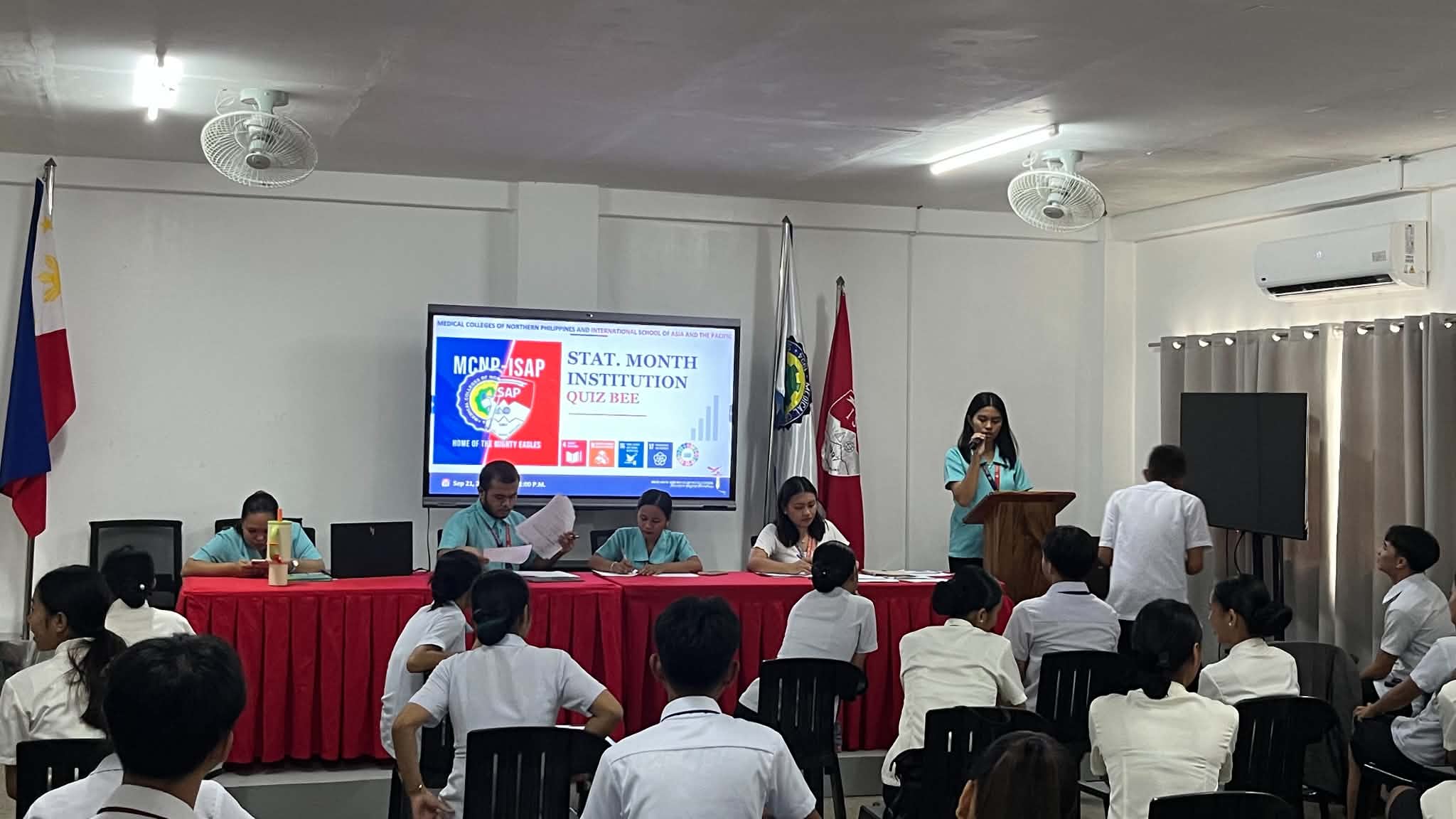 Quiz Bee competition floor with student contestants, board of judges, and proctors