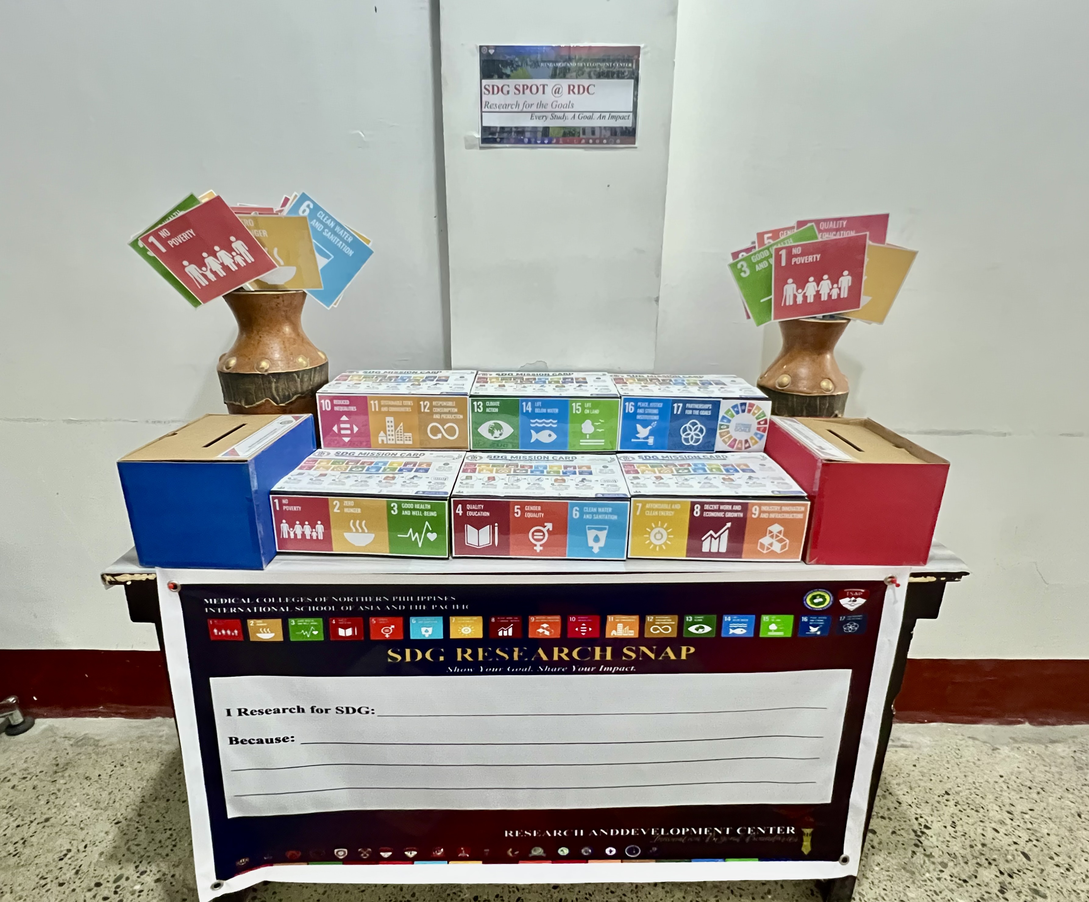 SDG SPOT corner table setup with Mission Cards and Research Snap banner